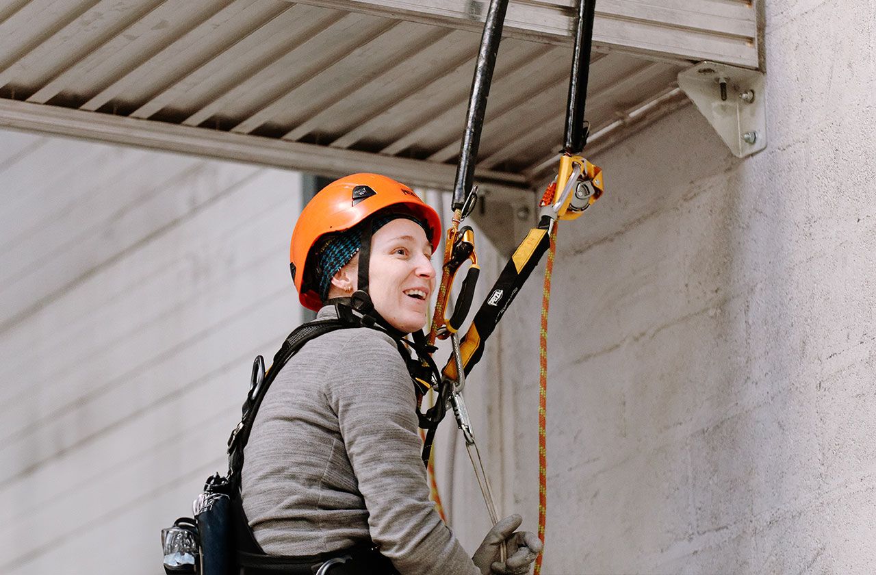 travailleuse en hauteur équipée d’un harnais et casque de sécurité