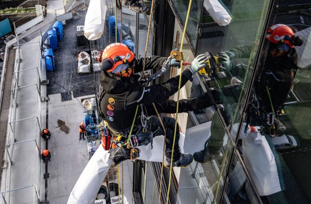 cordistes en suspension nettoyant une façade vitrée d’immeuble
